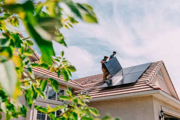 A photo of two electrician installing solar panels