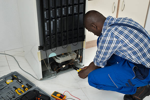 A photo of an electrician maintaining a refrigerator